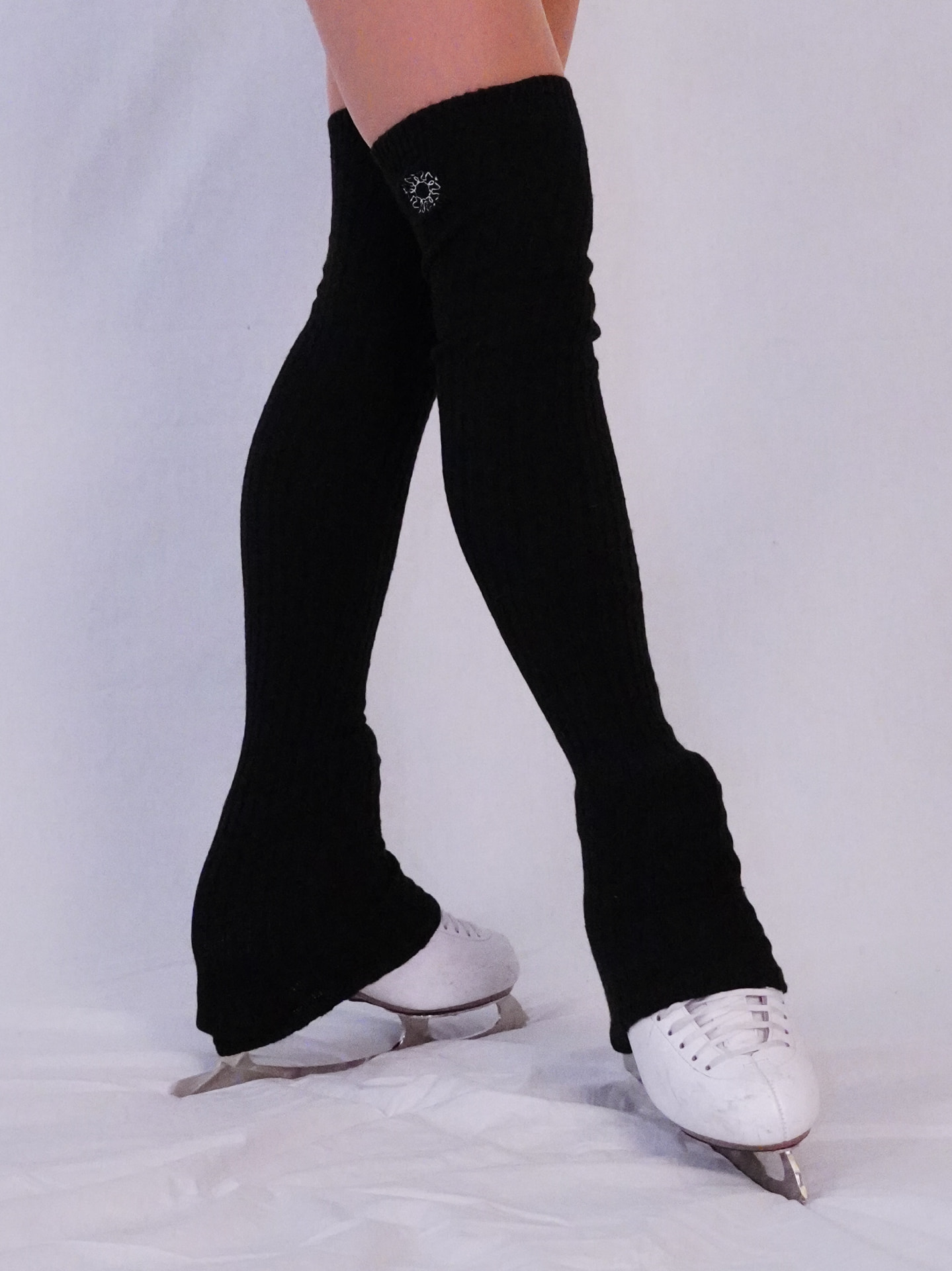 Model wearing long Black Swan legwarmers over white ice skates
