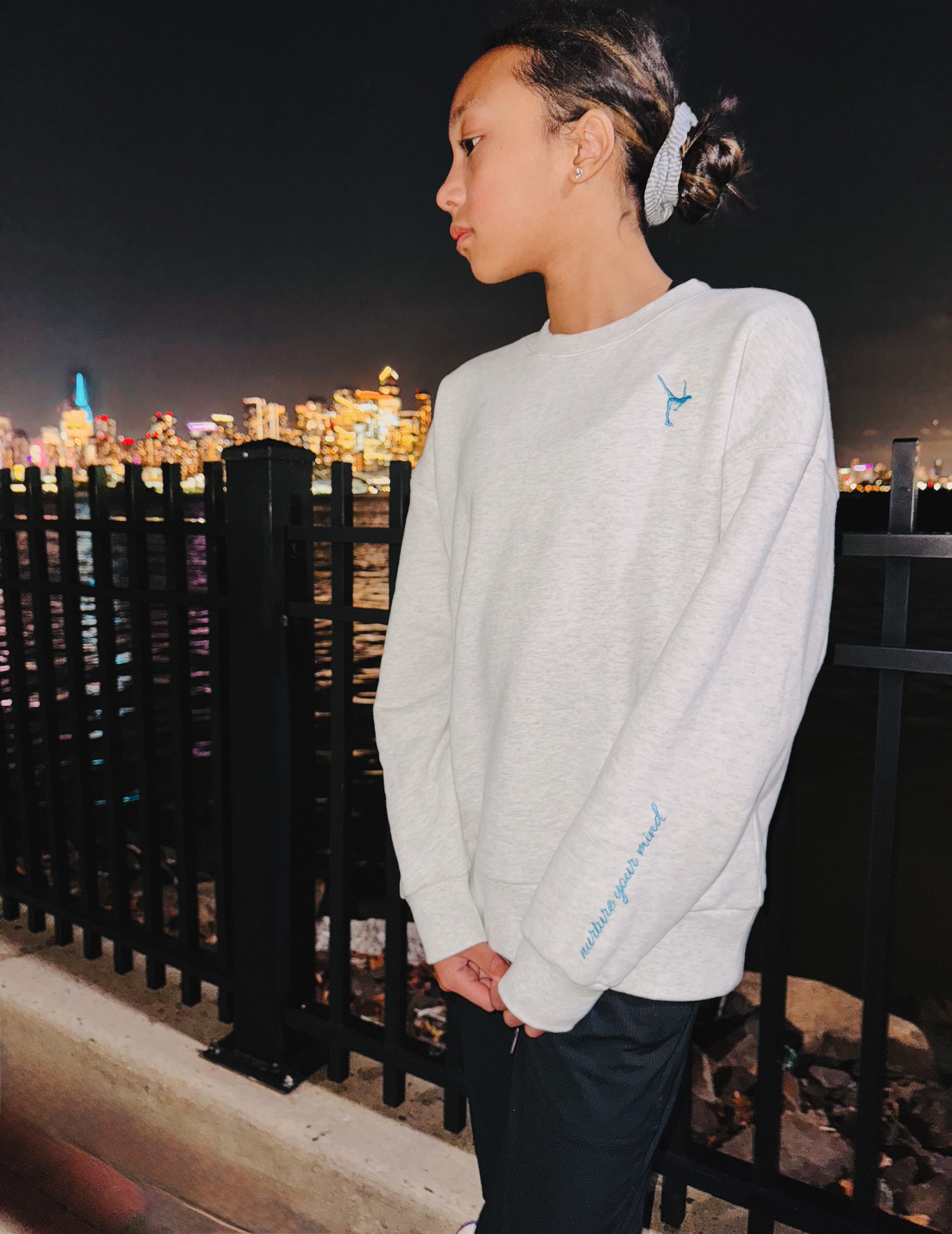 Skater wearing the mist Grace in Motion crewneck at night showing the sleeve detail